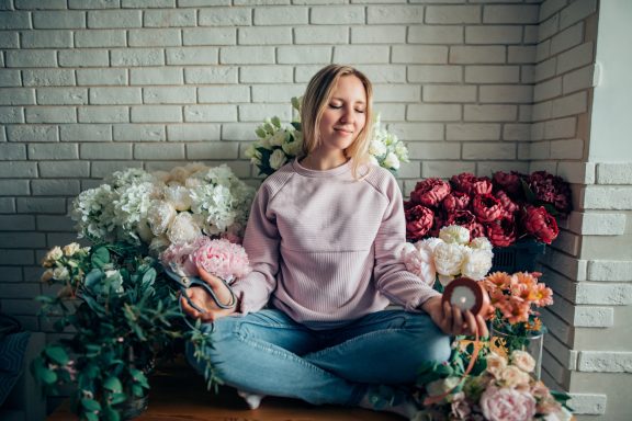 Mollit anim id est Smiling woman seated cross‑legged on floor, surrounded by bouquets of roses and foliage